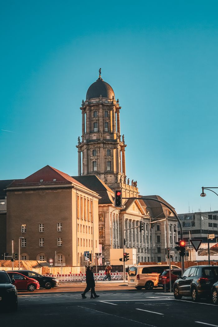 Street view of historic architecture with tower and traffic at sunset.